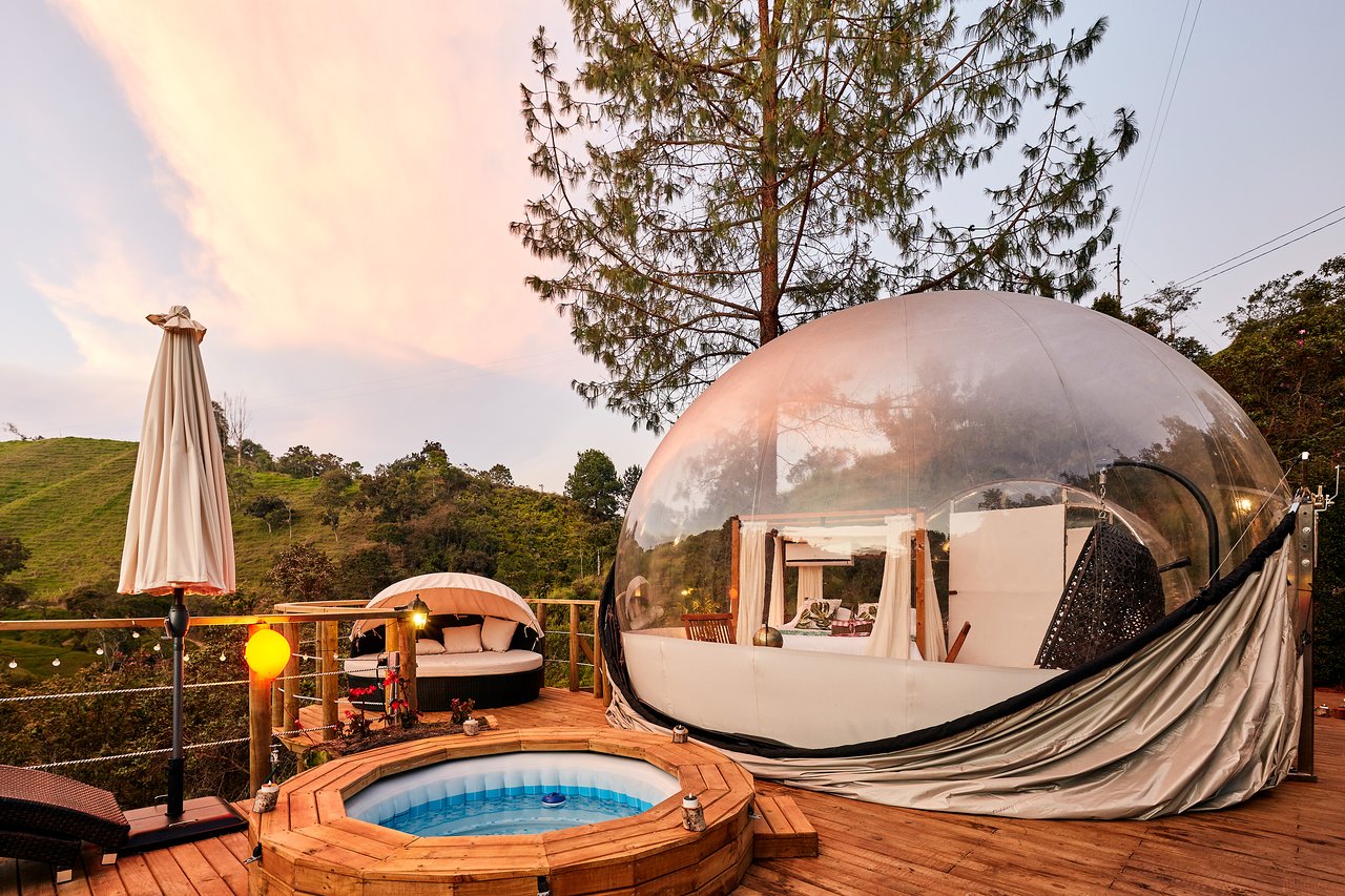 a glamping in the form of glass with a jacuzzi on a wooden platform